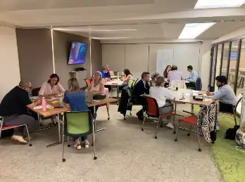 Une quinzaine de collaborateurs répartis autour de plusieurs tables pendant un atelier de création de jeu